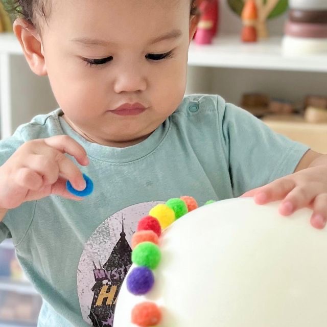 kid playing with pom poms